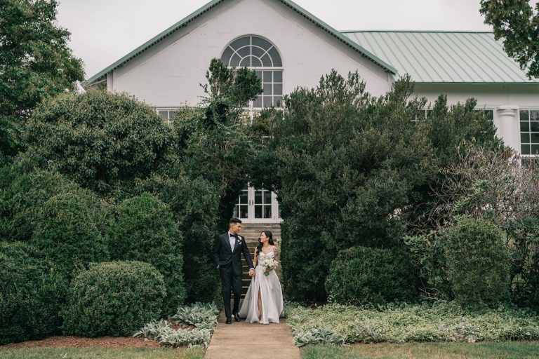 Bride and groom standing at entrance of ivy-covered building with arched window