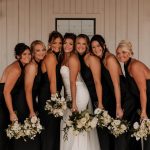 Bride and bridesmaids in coordinated black dresses holding white bouquets