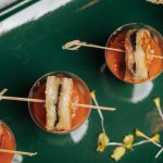 Grilled cheese sandwich bites served on wooden skewers in copper cocktail glasses