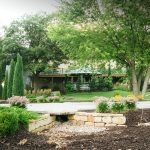 Outdoor courtyard garden space with paver patio, mature trees, and fire pit seating area