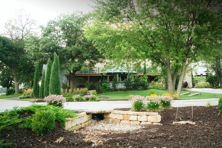 Outdoor courtyard garden space with paver patio, mature trees, and fire pit seating area