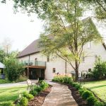 Rustic Nebraska barn wedding venue with curved walkway through manicured gardens and mature trees