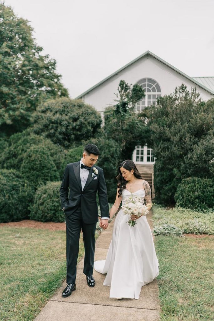 Couple holding hands walking on garden pathway at Northern Virginia wedding venue
