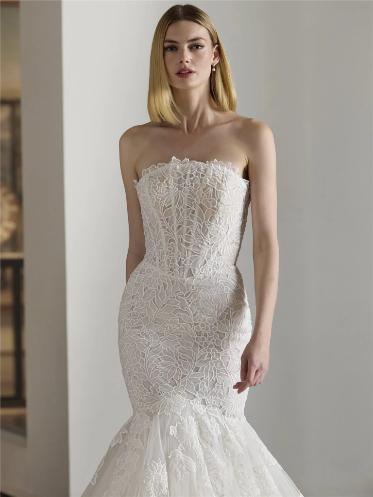 Strapless mermaid wedding gown featuring delicate floral lace overlay and flared tulle hem