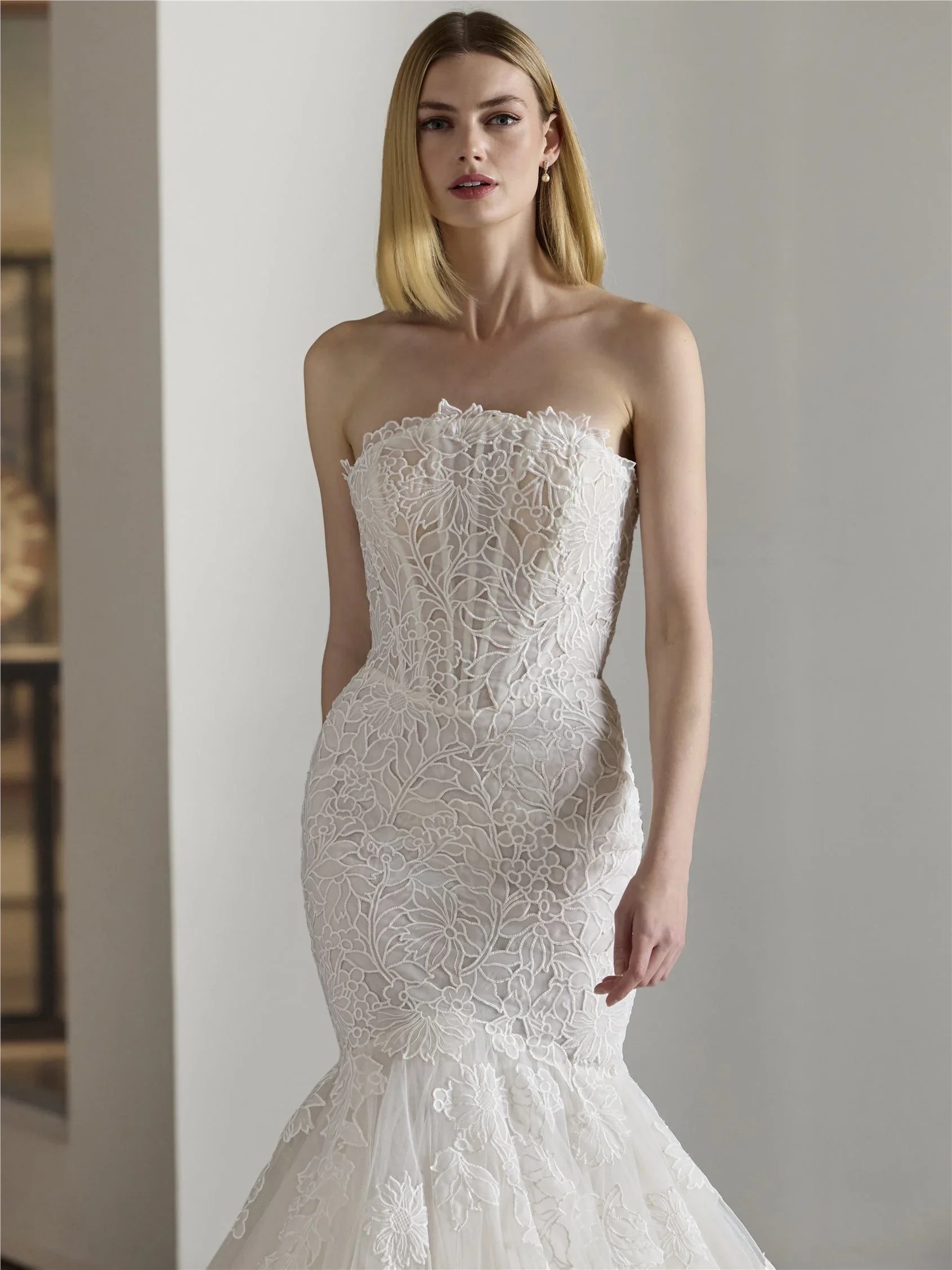 Strapless mermaid wedding gown featuring delicate floral lace overlay and flared tulle hem