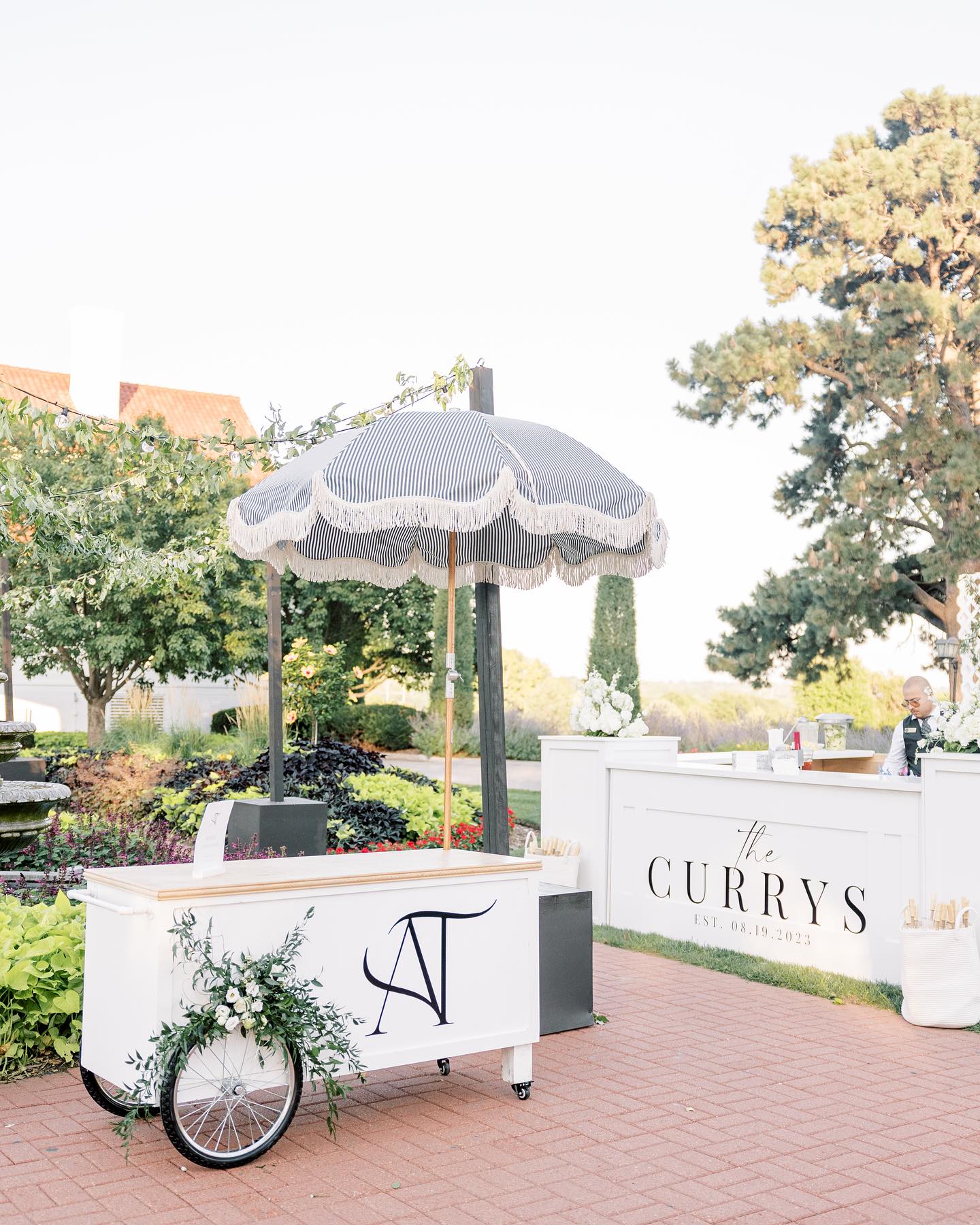 Custom wedding drink cart with navy monogram and matching beverage station in garden setting