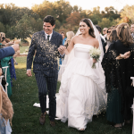 Newlyweds walking down aisle during confetti toss at outdoor autumn wedding celebration