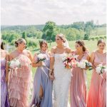 Bride and bridesmaids in pastel pink and lavender dresses walking together outdoors at Northern Virginia vineyard