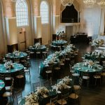 Elegant ballroom wedding reception with emerald green linens, white florals, and crystal chandeliers in historic venue