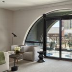 Modern living room with arched doorway, curved seating, and balcony with urban views