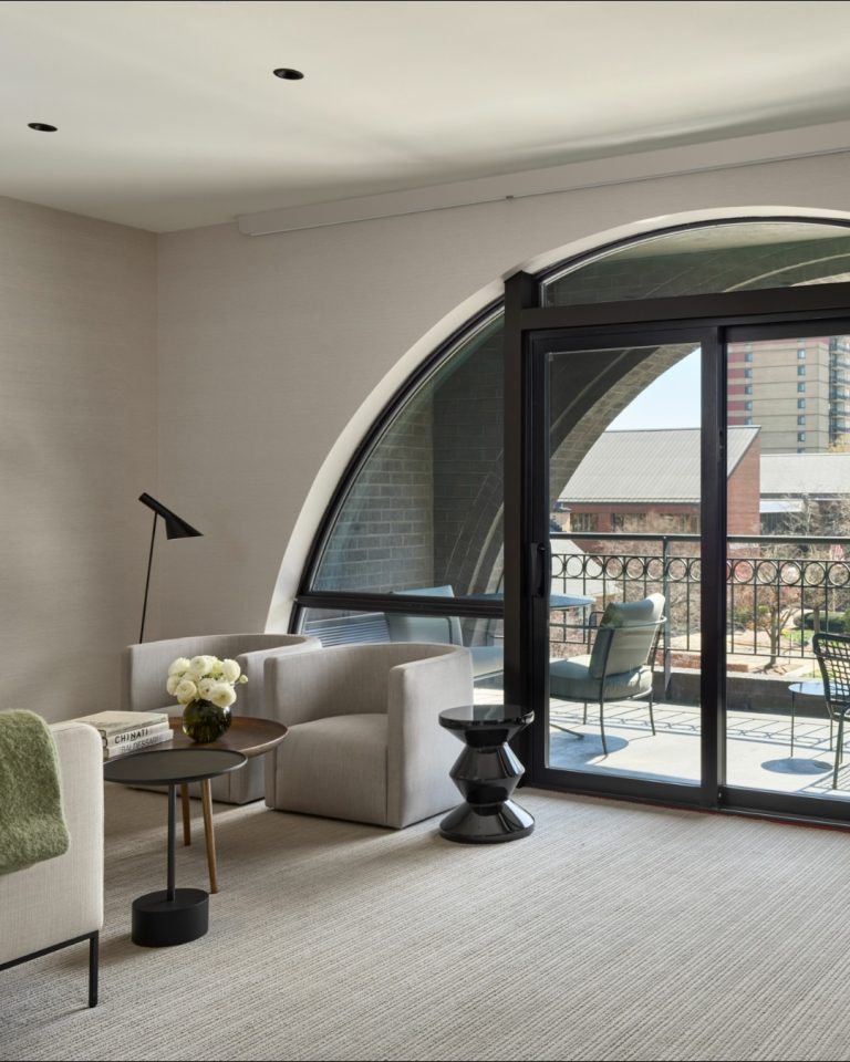 Modern living room with arched doorway, curved seating, and balcony with urban views