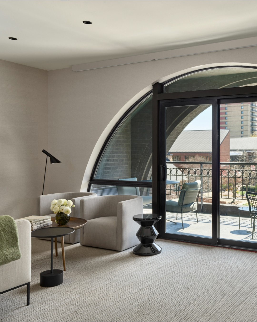 Modern living room with arched doorway, curved seating, and balcony with urban views