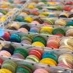 Colorful French macarons arranged in rows in clear display trays showing variety of flavors and colors