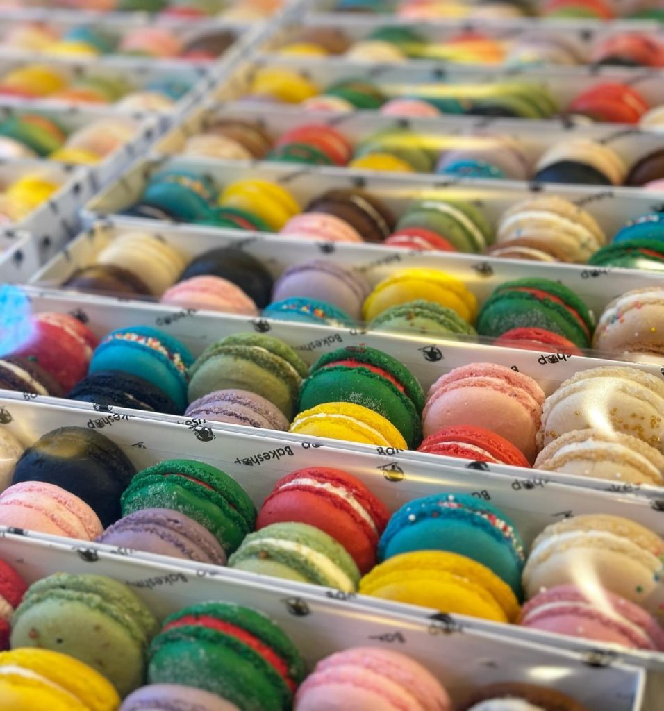 Colorful French macarons arranged in rows in clear display trays showing variety of flavors and colors