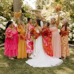 Bride with bridesmaids in colorful pink and coral dresses celebrating outdoors at Lilac Hill venue