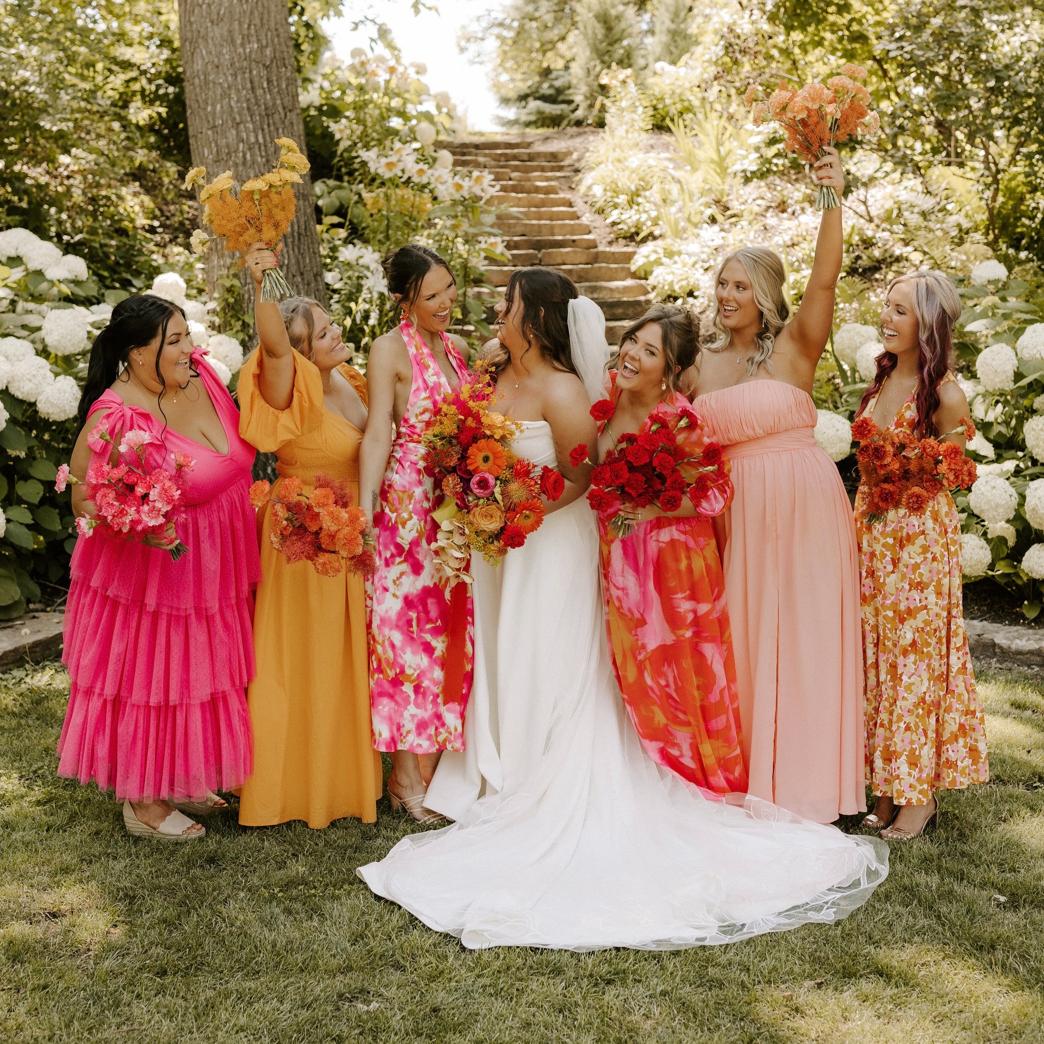 Bride with bridesmaids in colorful pink and coral dresses celebrating outdoors at Lilac Hill venue