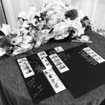 Wedding reception table displaying photo booth strip guestbooks with handwritten messages and elaborate white floral centerpiece