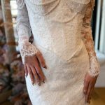 Ivory lace wedding dress with off-shoulder neckline, pearl-trimmed corset bodice, and fitted mermaid skirt with floral embroidery
