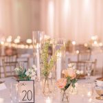 Close-up of modern wedding table centerpiece with cylinder vases, mixed blooms, and table 20 marker on white linen