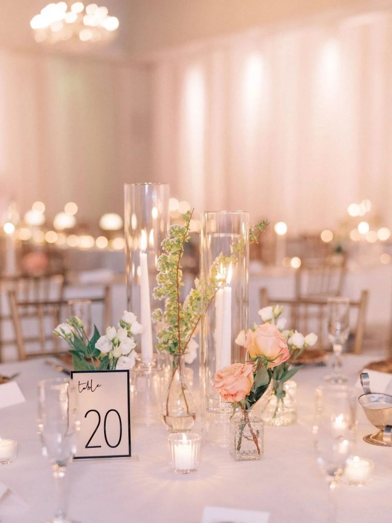 Close-up of modern wedding table centerpiece with cylinder vases, mixed blooms, and table 20 marker on white linen