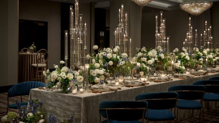 Formal dining table featuring tall glass candelabras and white rose arrangements with navy upholstered seating