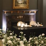 Elegant dessert display on dark wood mantel adorned with white floral arrangements and candlelight