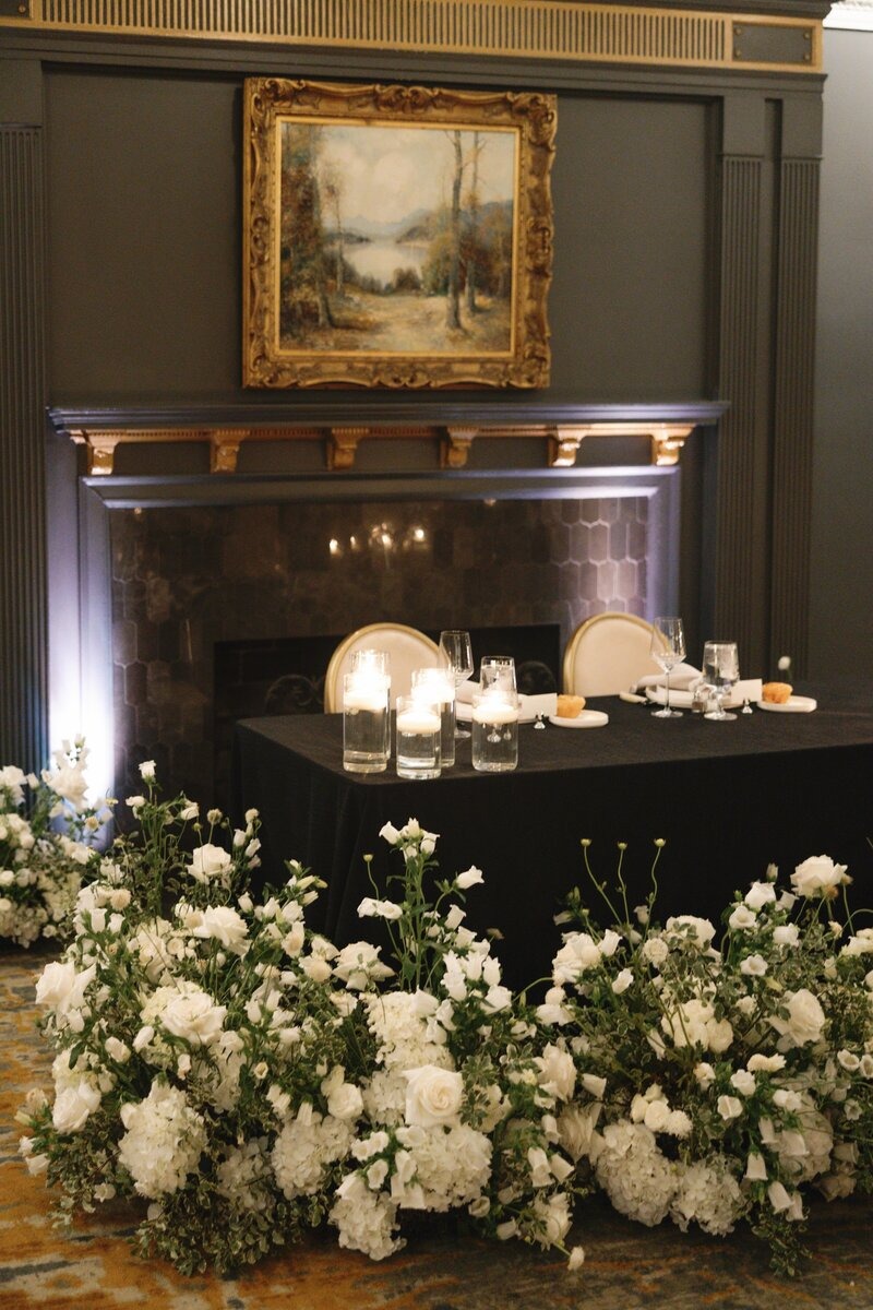 Elegant dessert display on dark wood mantel adorned with white floral arrangements and candlelight