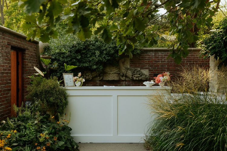 Wedding rental bar in white with botanical styling and brick courtyard setting