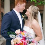 Bride and groom gazing at each other holding vibrant pink and coral peony bouquet at Nebraska wedding venue