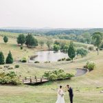 Bride and groom at Northern Virginia vineyard wedding venue with pond, rolling hills, and mountain views