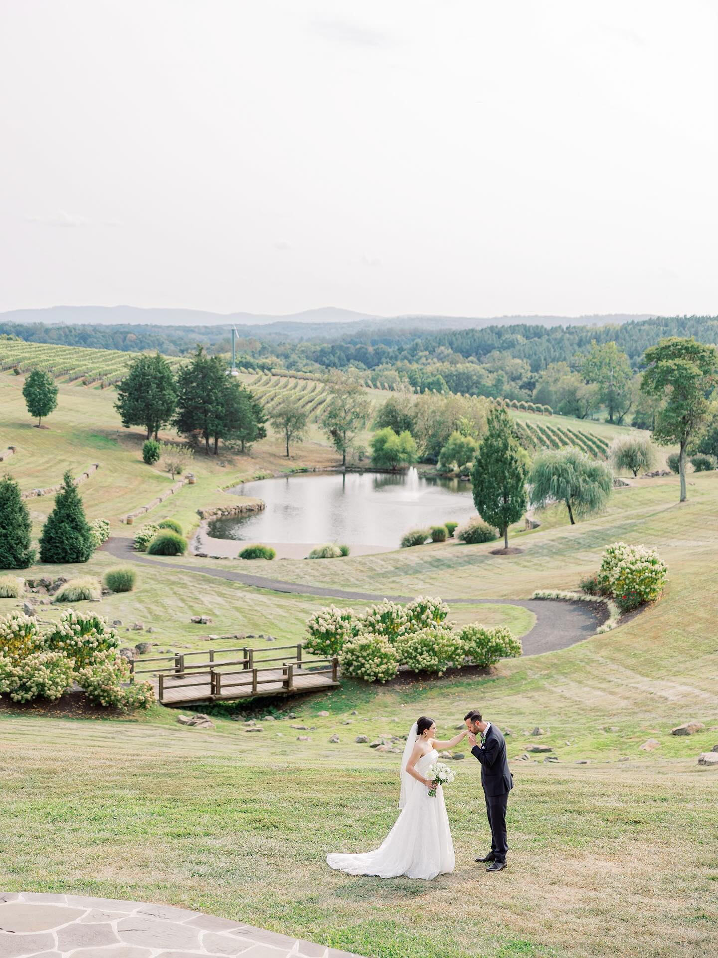 Bride and groom at Northern Virginia vineyard wedding venue with pond, rolling hills, and mountain views
