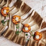 Grilled peach appetizers with cream cheese arranged on decorative gold platter