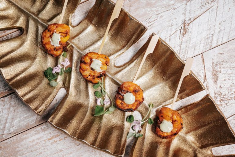 Grilled peach appetizers with cream cheese arranged on decorative gold platter