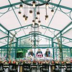 Glass greenhouse reception venue with ornate chandeliers and garden views