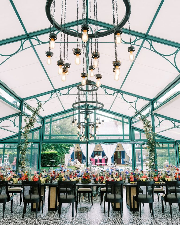 Glass greenhouse reception venue with ornate chandeliers and garden views