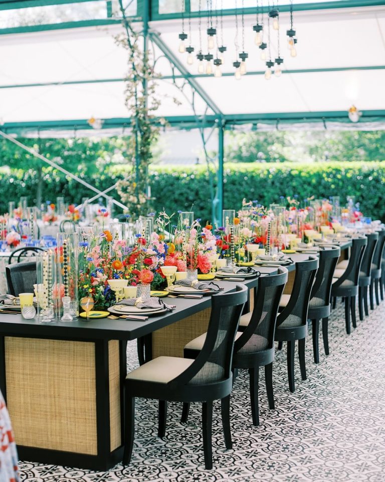Greenhouse wedding reception with long dining tables, vibrant centerpieces, and mosaic tile flooring