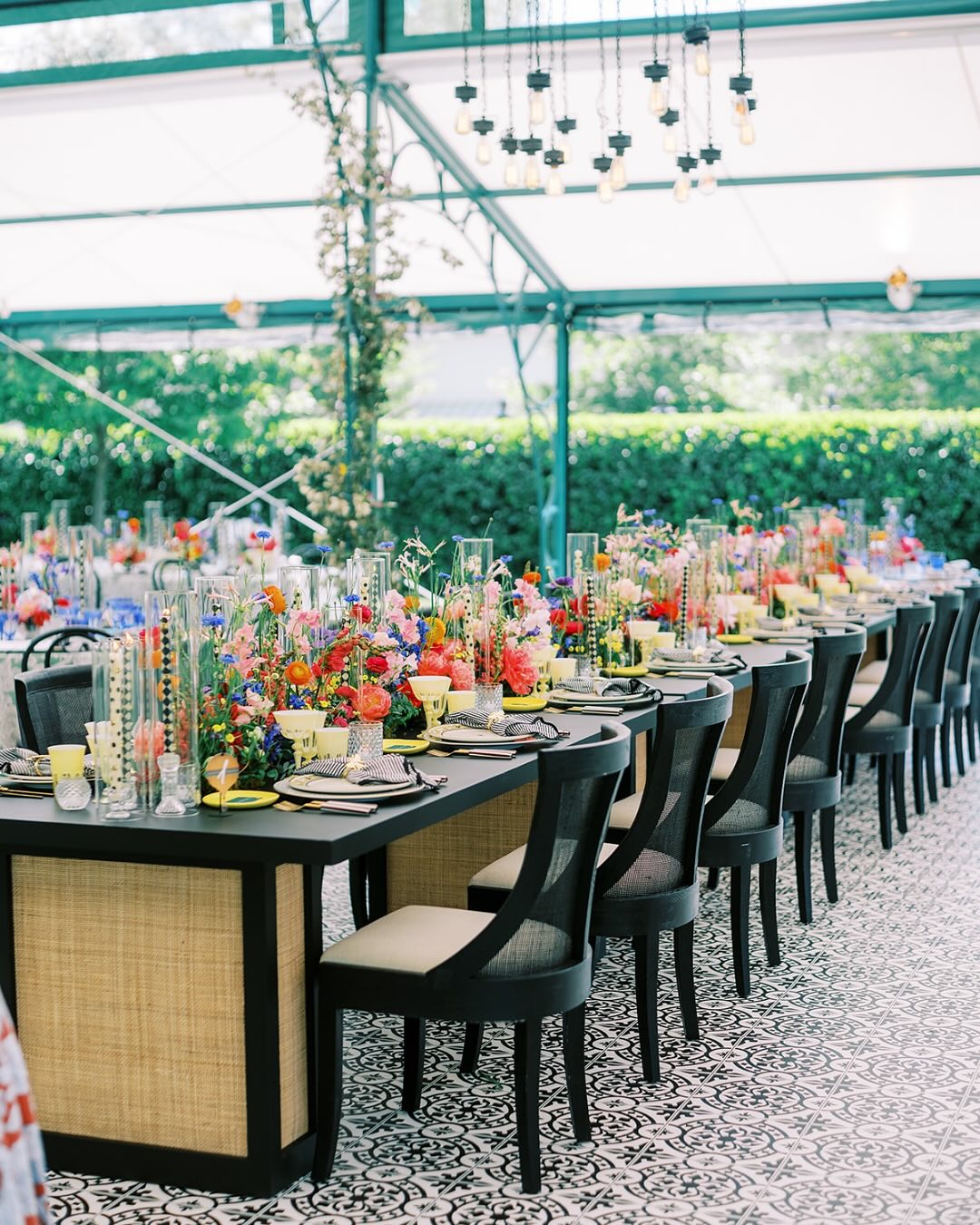 Greenhouse wedding reception with long dining tables, vibrant centerpieces, and mosaic tile flooring