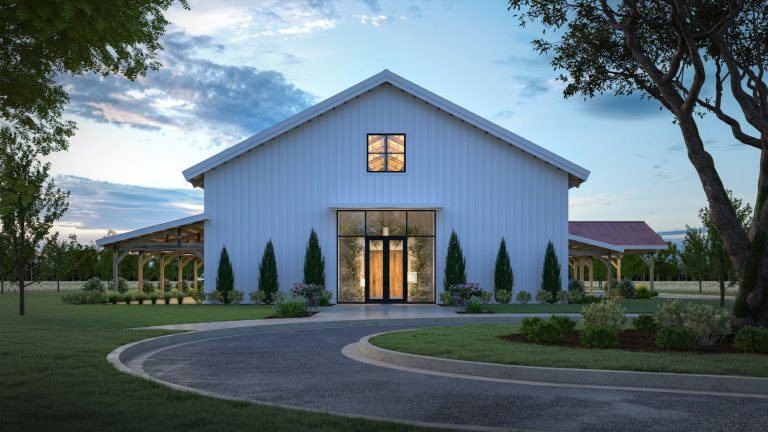 Modern white barn-style wedding venue with illuminated entrance, cypress trees, and circular driveway at dusk