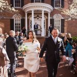 Joyful newlyweds walking down aisle after ceremony at historic brick venue surrounded by cheering guests