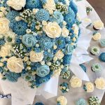 Close-up detail of blue and ivory floral wedding cake with coordinating cupcakes