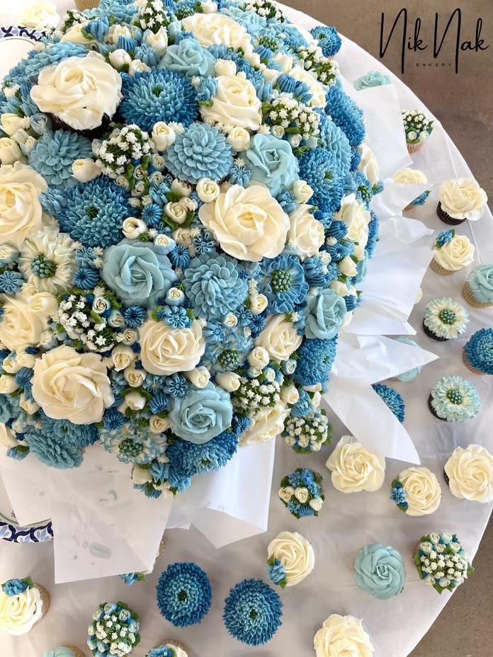 Close-up detail of blue and ivory floral wedding cake with coordinating cupcakes