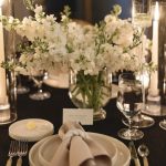 Close-up of wedding reception table with white floral centerpiece and elegant place setting
