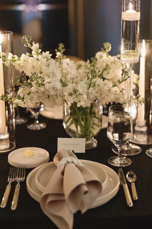 Close-up of wedding reception table with white floral centerpiece and elegant place setting
