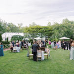 Outdoor wedding reception with white tent and guests mingling on lawn