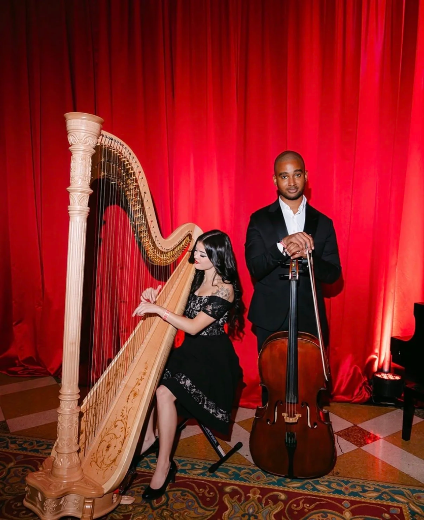 Harpist and cellist performing elegant wedding ceremony music with red curtain backdrop
