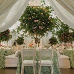 Tented wedding reception with tall tree centerpieces adorned with pink roses