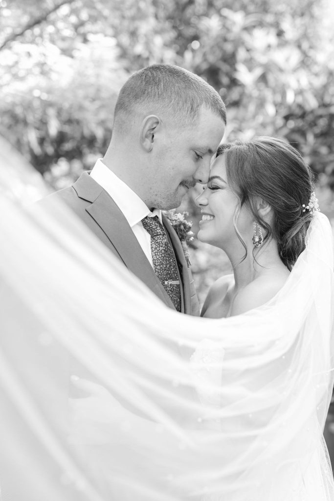 Bride and groom sharing tender forehead-to-forehead moment framed by veil