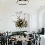 Round reception table with dramatic tall centerpiece of roses, greenery, and curly willow branches