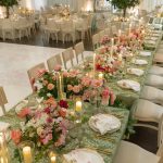 Wedding reception tables decorated with pink flowers and candles under tent