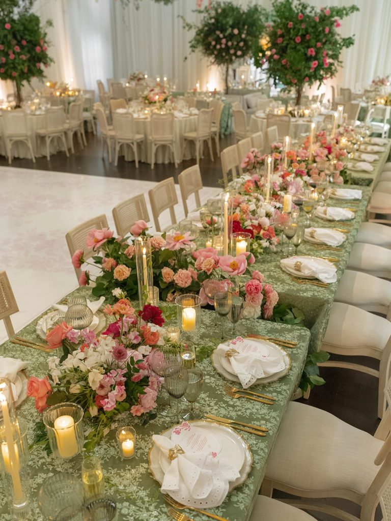 Wedding reception tables decorated with pink flowers and candles under tent